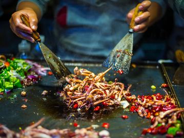 Asian-style squid stir-fry being cooked on a hot griddle with vegetables and chili.