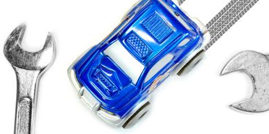 A blue toy car surrounded by two metal wrenches on a white background.