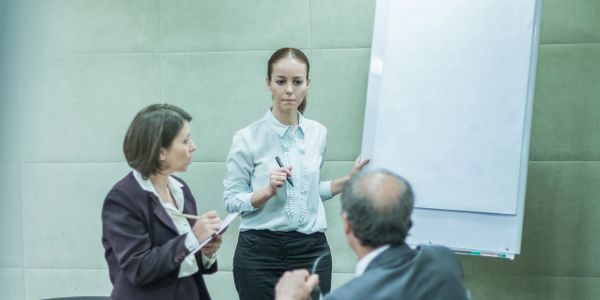 Business meeting with a woman presenting and colleagues listening attentively.