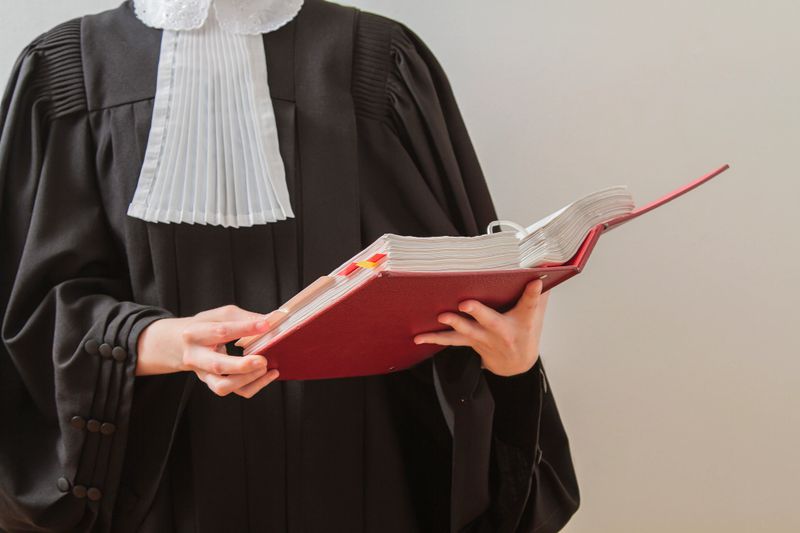 canadian lawyer in toga, reading from a red law book