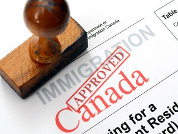 A wooden stamp marking an immigration document approved for Canada.