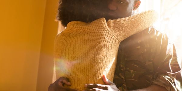 A warm embrace between a woman and a soldier in sunlight.