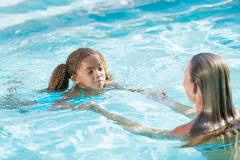 Little girl (5 years) with swim instructor (30s).