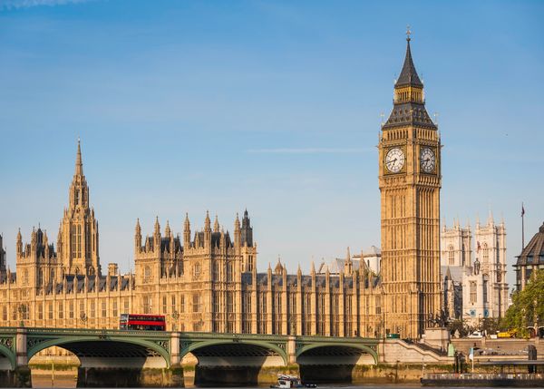 Big Ben and the Houses of Parliament in London with a red bus crossing the bridge.