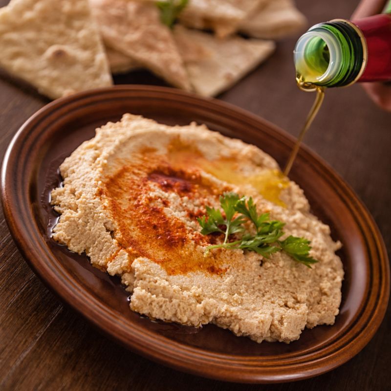 Bowl with hummus having olive oil poured over it.