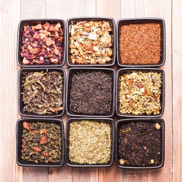 Nine square bowls filled with various colorful dried herbs and spices.