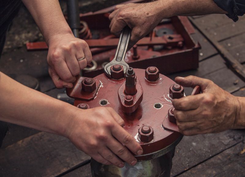 The two working hands are tightening the big nut with a wrench at the factory