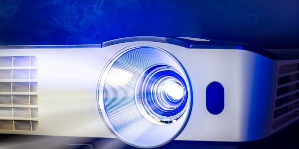 Close-up of a projector lens emitting blue light.