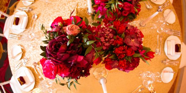 Elegant floral centerpiece with red and pink flowers on a banquet table.