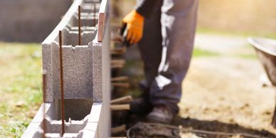 Construction worker building a concrete block wall with rebar.