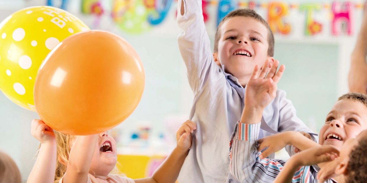 Children joyfully playing with balloons at a birthday party.