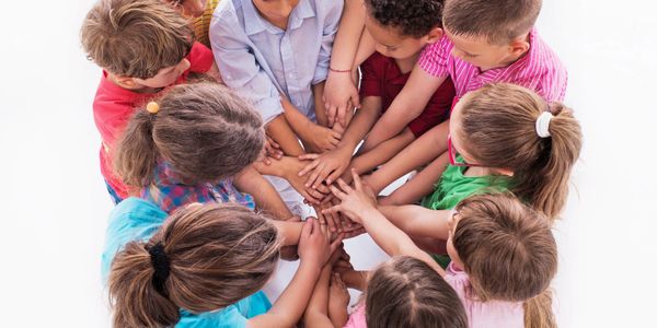 Children forming a circle with hands joined together in the center.