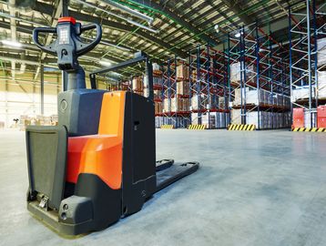 Electric pallet jack in a spacious warehouse with stacked pallets.