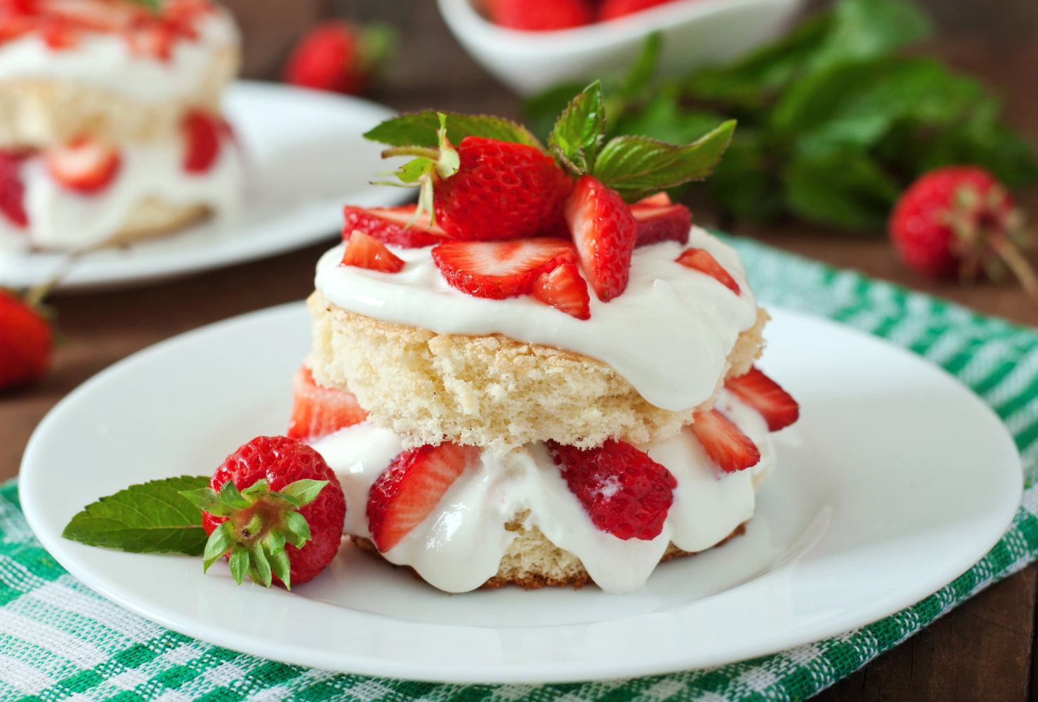 Mini strawberry shortcake with fresh cream and mint on a white plate.