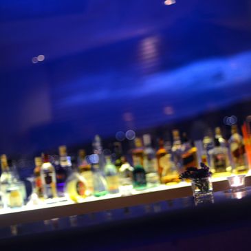 Blurred image of a bar counter with illuminated bottles and candles.