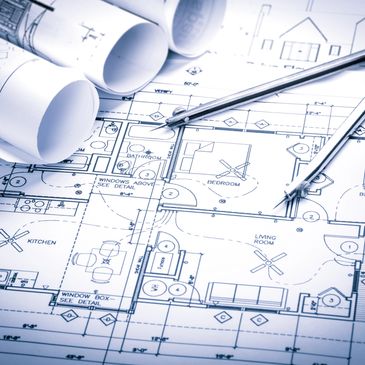 Architectural blueprints with a compass and rolled-up plans.