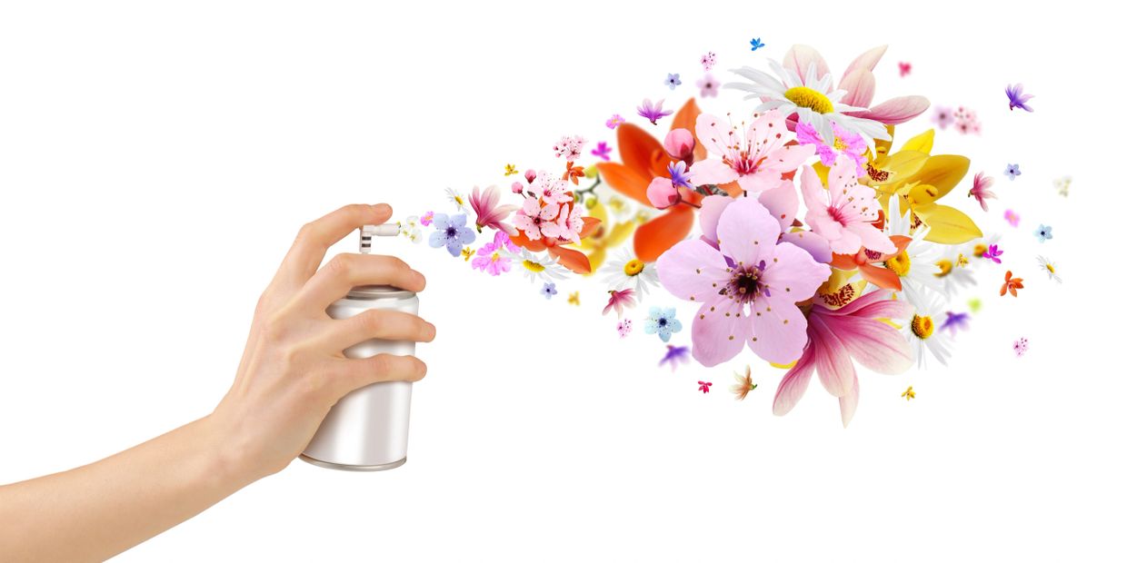 Hand spraying colorful flowers from a white spray can.