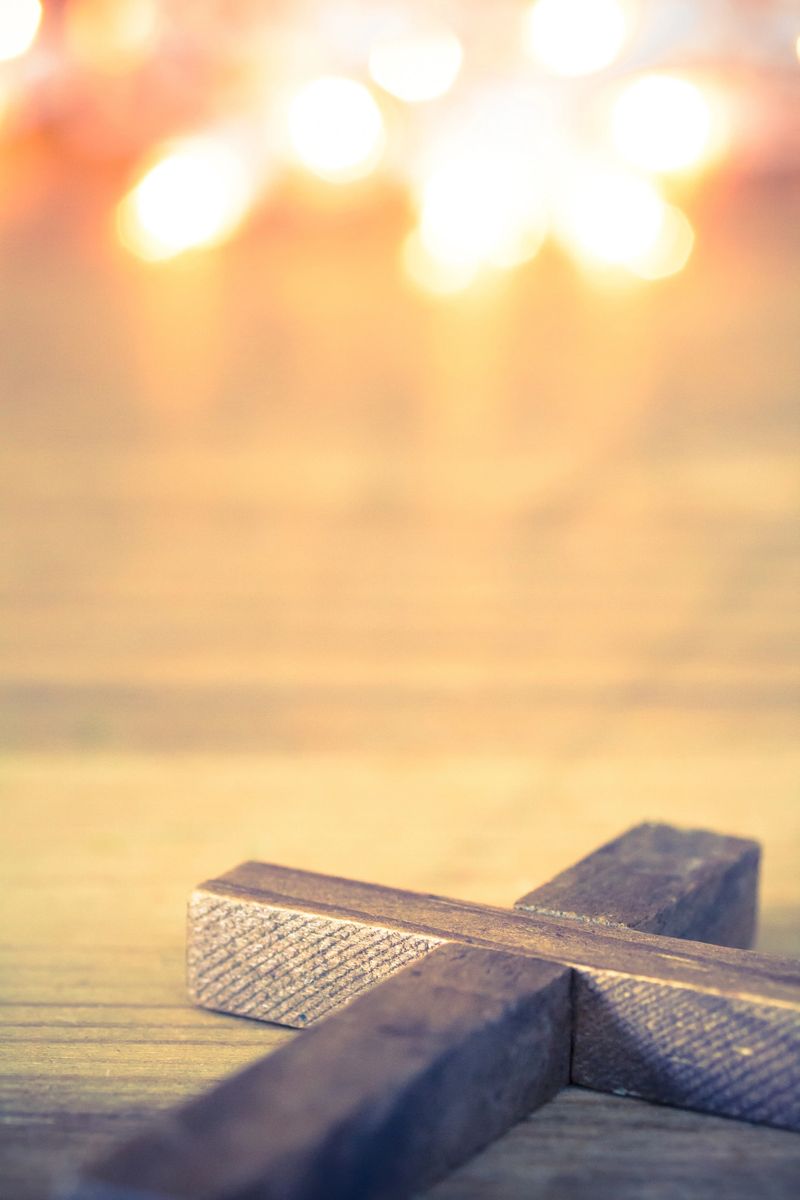 A wooden Christian cross with a soft bokeh lights background.