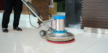 Floor polishing machine cleaning white tiled floor.
