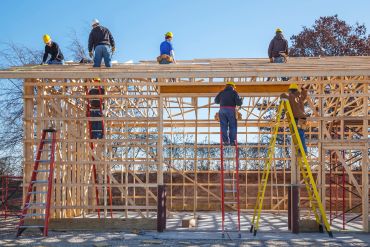 Wooden frame construction of a building under a cloudy sky.