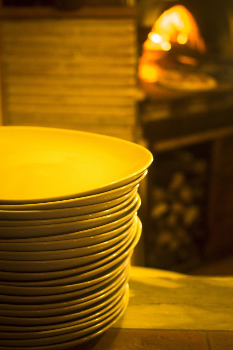 Italian pizzeria traditinal wood fire oven pizza and stack of plates in restaurant in Rome Italy.