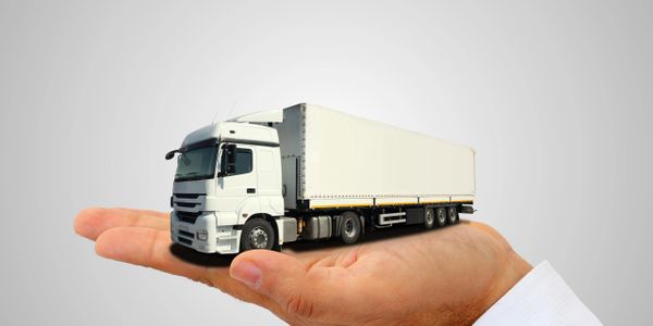 A small white truck resting on an open human hand.