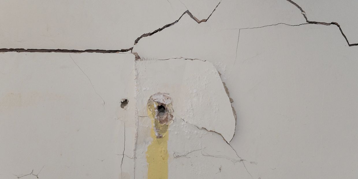 Damaged drywall with cracks and holes