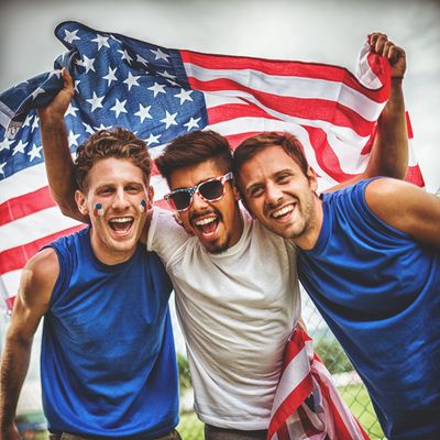 Three friends joyfully celebrating with an American flag.