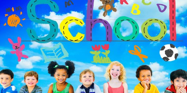 Happy children smiling under a colorful 'School' banner with playful drawings.