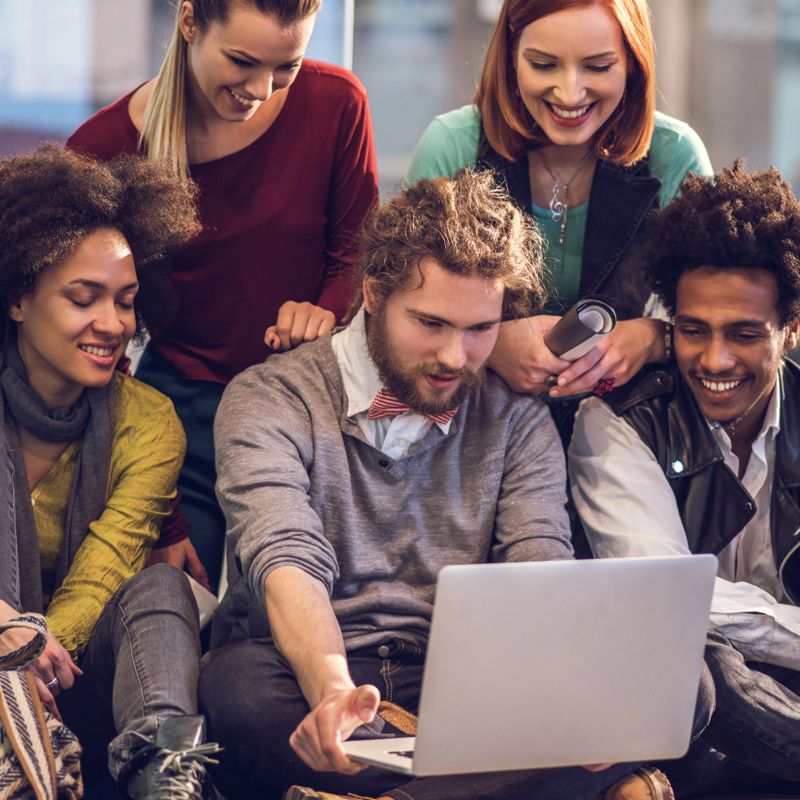 Young start-up team cooperating while using computer together.