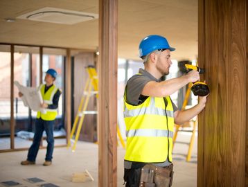 Construction worker installing wooden panels indoors.