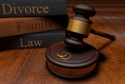 Gavel with wedding rings and law books on a wooden surface.