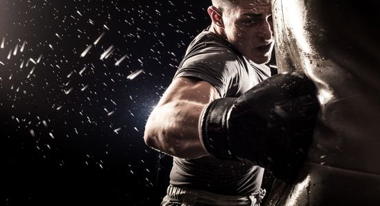 Empty boxing gym with heavy bags and a ring.