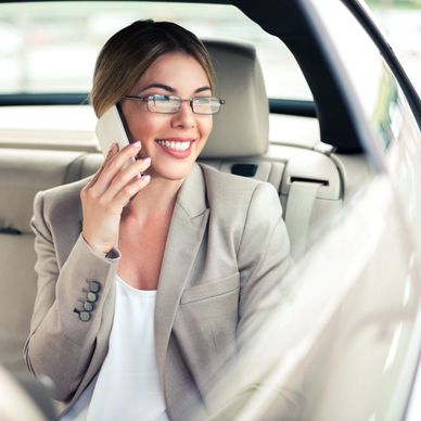Smiling woman talking on phone in car.