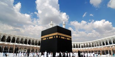 The Kaaba in Mecca with pilgrims around it under a bright sky. Many pilgrims in the picture are performing Umrah. Reverts Umrah are here to assist the revert community in their trip.