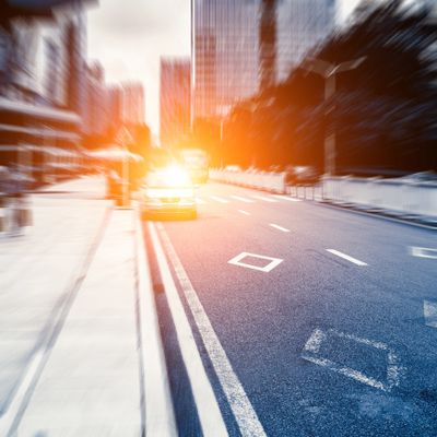 A blurred city street with a bright car light shining towards the camera.