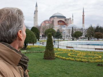 Man admiring the historic Hagia Sophia in Istanbul from a park.