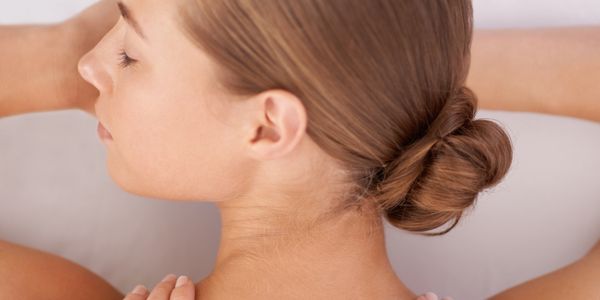 Woman with hair bun receiving a shoulder massage.