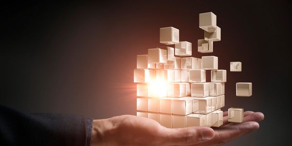 Hand holding a glowing 3D cube with floating smaller cubes.