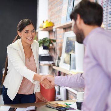 Two professionals shaking hands in a modern office setting.
