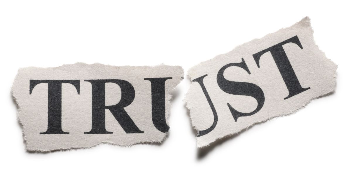 Torn paper spelling "TRUST".