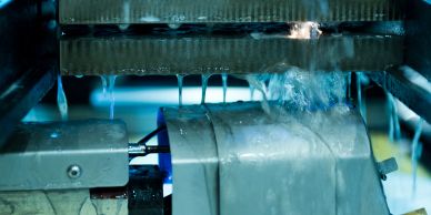 Water flows over a machine part in an industrial setting.