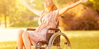 Happy woman in a wheelchair enjoying sunshine outdoors.