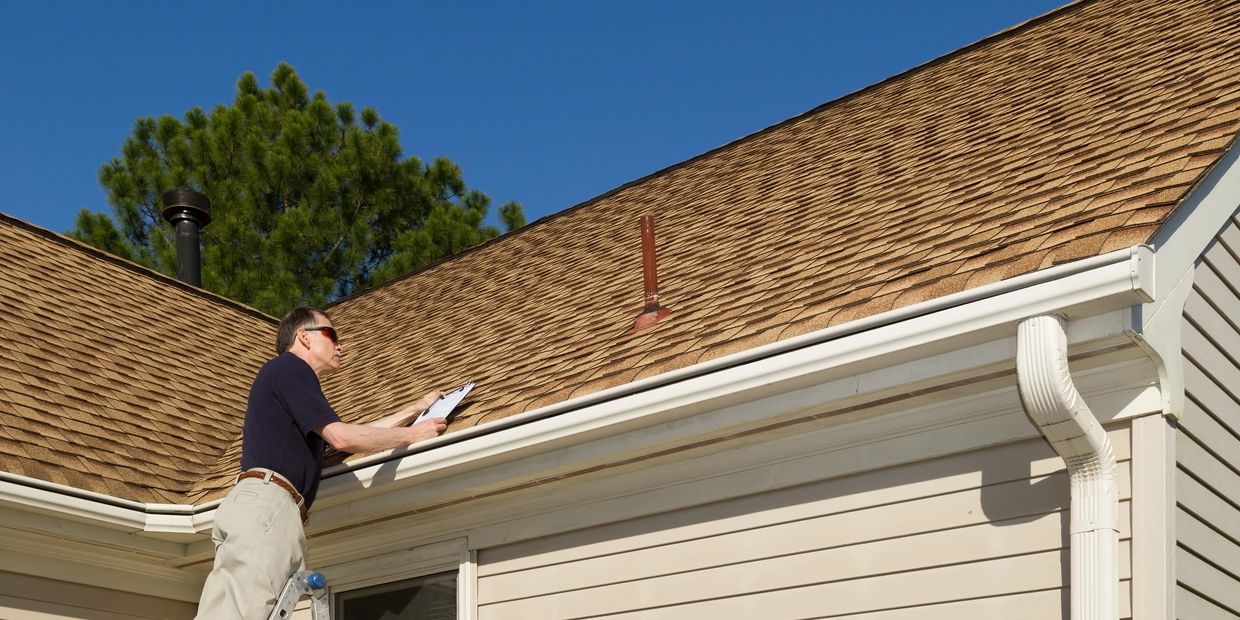 Home inspector examining a residential roof in the field.
