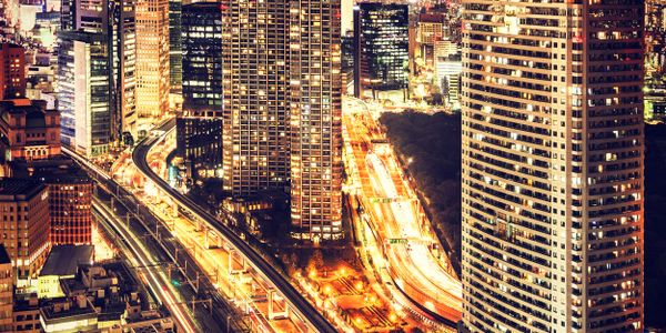 A vibrant cityscape at night with illuminated skyscrapers and busy highways.