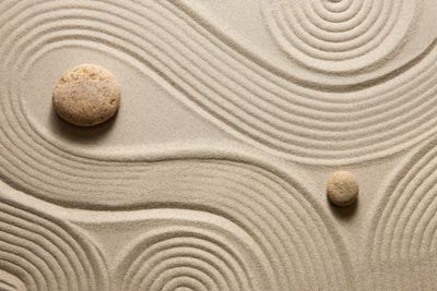 Zen garden sand with smooth stones and flowing patterns.