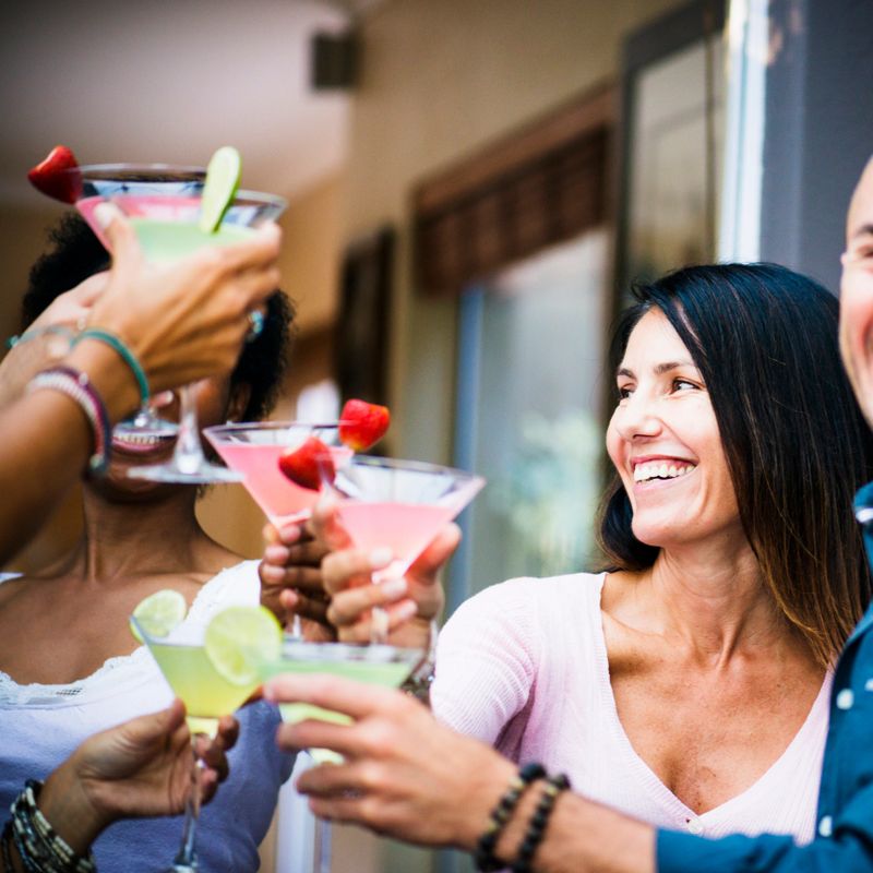 Group of happy friends enjoying conversation, cocktails & time together at an indoor bar
