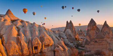 Hot air balloons over rocky landscape at sunrise.