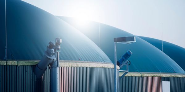 Large industrial biodigesters with sunlight in the background.