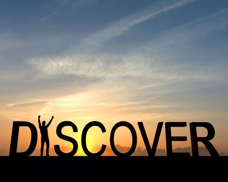 The word discover is silhouetted against an orange and blue sunset. The I in the word is made from a figure with their arms raised up in the air in a successful victory pose.